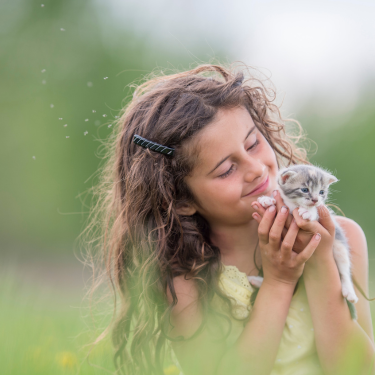 Girl playing with kitten outside.