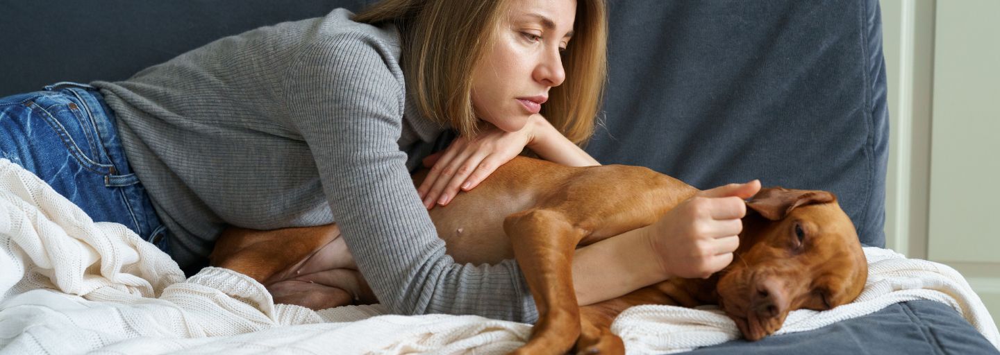 Worried woman taking care of her ill dog.