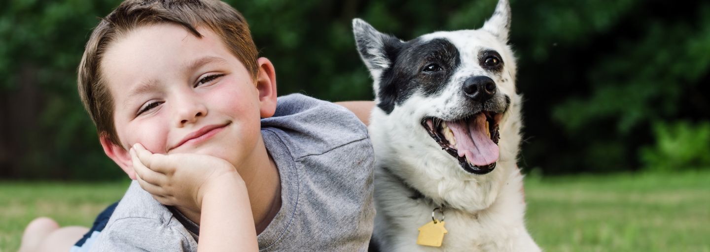 Child and dog laying together in park happily 