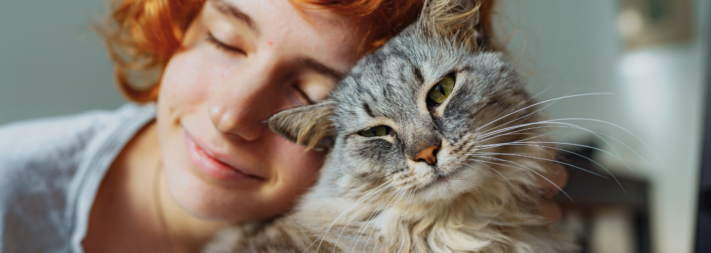 large cat rubbing against red hair woman face