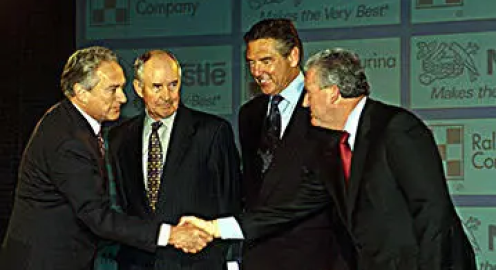 Four men at an event and two of them shaking hands