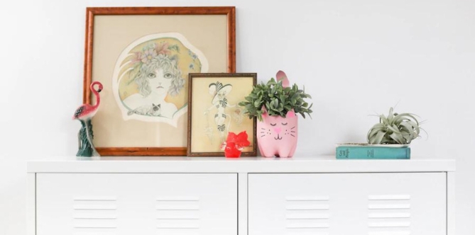 drawings and plant on top of white cabinet